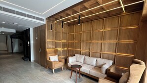 Un hall d’entrée moderne avec un canapé modulable, des fauteuils et une petite table.