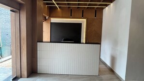 Un comptoir d’accueil moderne, doté d’un panneau décoratif en bois et d’un plan de travail noir.