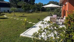 A well-maintained garden with a patio area, outdoor furniture, and a white umbrella. - Aux Aigrettes (Gousse)