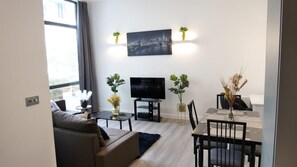 Un salon moderne doté d’un téléviseur à écran plat, d’un canapé, d’une table à manger avec des chaises et de plantes décoratives.