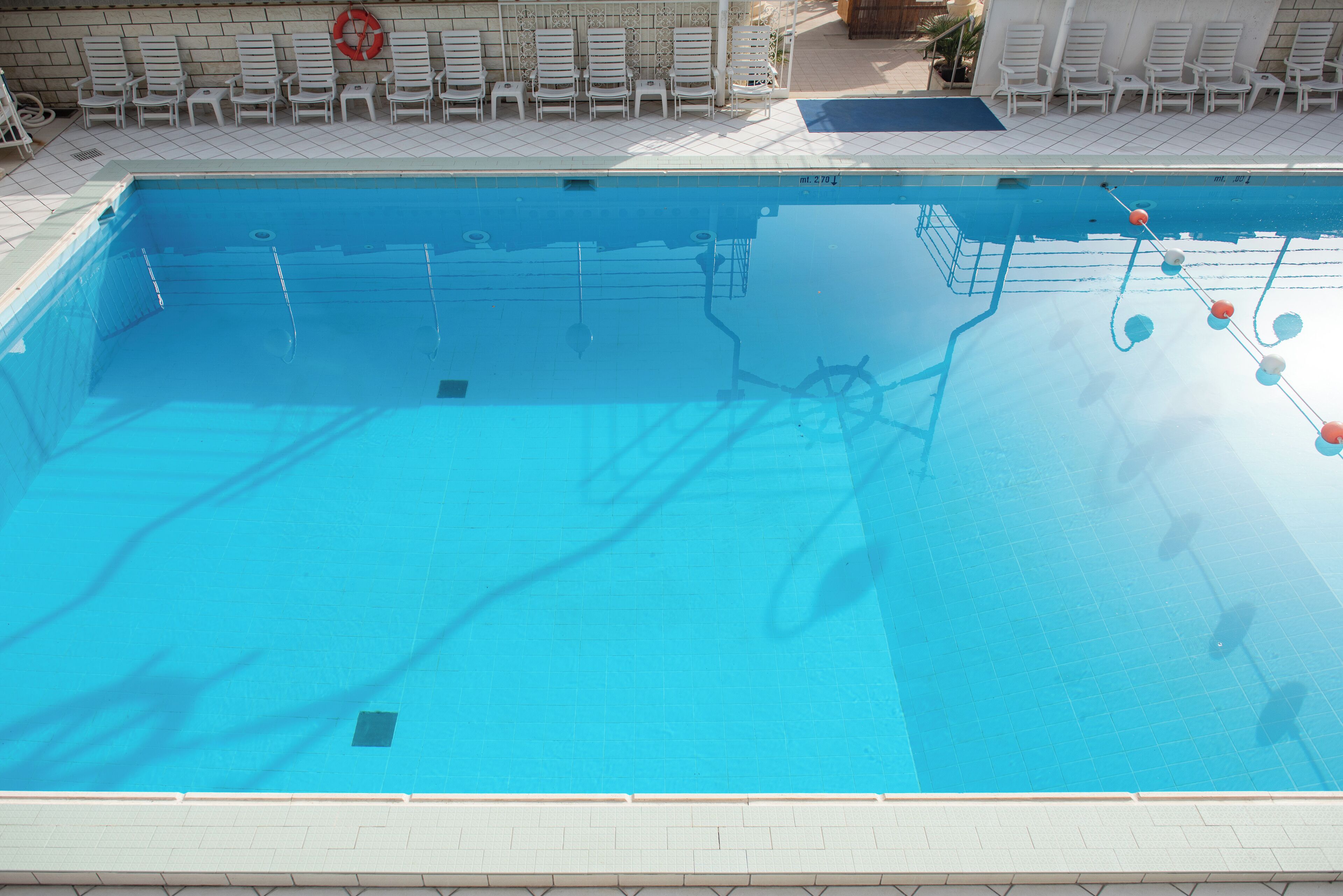 A clear blue swimming pool with a lifebuoy and pool ladder.