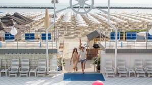 A pool area with lounge chairs, a pink flamingo float, and a ship's wheel decoration. - Hotel Flamingo (Gatteo)