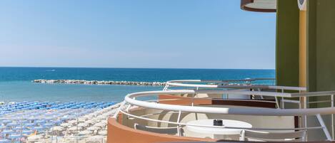 A balcony with a view of the sea and beach umbrellas.