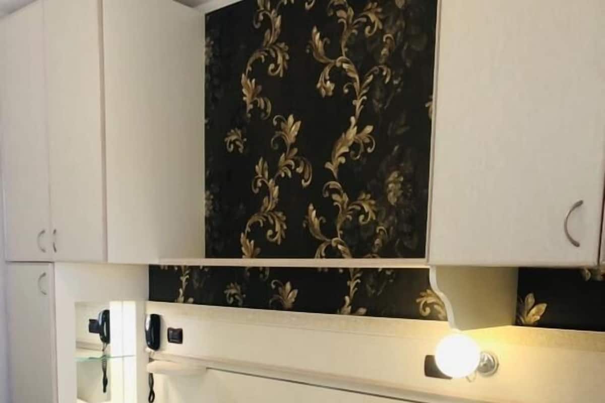 A hotel room with a bed, bedside table, and a mirror.