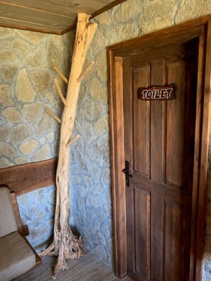 A wooden door with a sign that reads "TOILET" and a large tree trunk leaning against the wall. - Holiday Home Jela (Gospic)