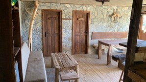 A rustic wooden interior with a bench, a table, and two doors marked "TOILET". - Holiday Home Jela (Gospic)