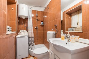 A bathroom with a shower, toilet, sink, and a towel rack. - Studio Toniko (Split)