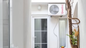 Un couloir étroit, doté d’un sol carrelé, d’une porte et d’une fenêtre donnant sur des vélos et un bâtiment à l’extérieur.