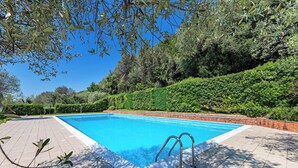 A swimming pool with a tiled deck and metal ladder, surrounded by lush greenery and a brick wall. - Residence San Giorgio by Wonderful Italy (Toscolano Maderno)