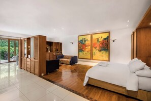 Un dormitorio moderno con una cama grande, un sofá, un armario de madera y un cuadro.