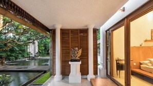 Recepció d'hotel amb una font, una estàtua i una zona de seients amb vista al jardí.