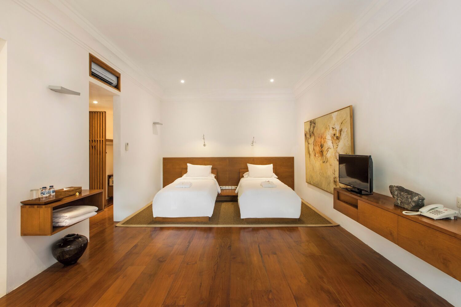 Habitación doble con dos camas, televisión, teléfono y un cuadro en la pared.