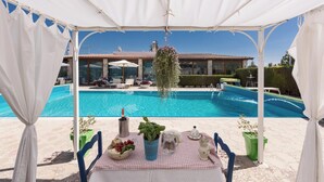 Un espacio al aire libre cubierto con una piscina, una mesa dispuesta con comida y bebidas, y una planta colgante.