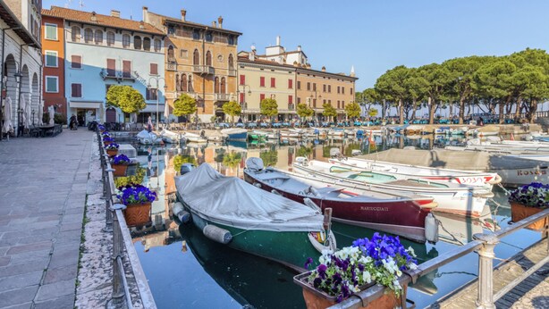 A canal with boats docked, surrounded by historic buildings and trees. - C'era una volta in centro by Wonderful Italy (Desenzano del Garda)