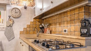 A kitchen with a gas stove, a clock, and a coffee maker. - C'era una volta in centro by Wonderful Italy (Desenzano del Garda)