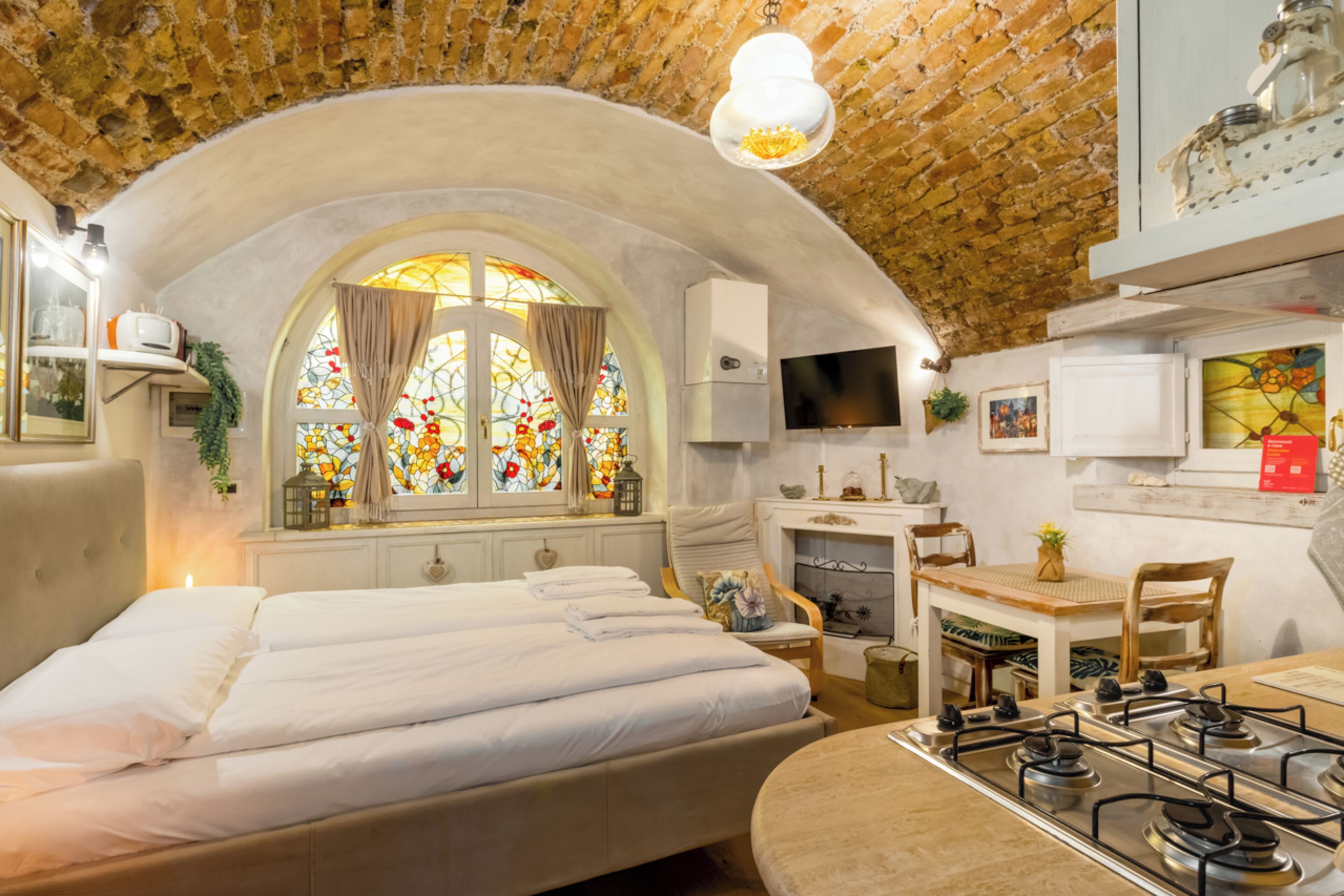 Una habitación acogedora con cama, escritorio, silla, fogones y televisor.