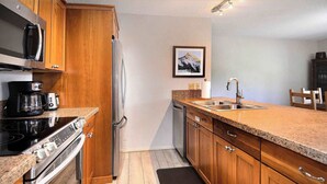 A kitchen with wooden cabinets, a stainless steel refrigerator, a coffee maker, and a dishwasher. - Ponderosa Place, Walk to slopes, Hot tub! (Mt. Crested Butte)