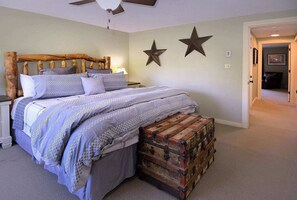 Un dormitorio con cama, cabecera de madera, un banco y dos estrellas en la pared.
