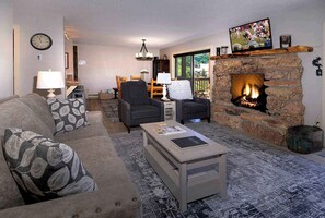 Una sala de estar con chimenea, un sofá, una mesa de centro y un televisor.