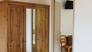 A bedroom with a wooden wardrobe, a bed with a white towel, and a dining area visible through an open door. - Nice apartment for 6 guests with pool, A/C, WIFI, TV, terrace and pets allowed (Monticello)