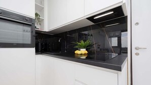 A modern kitchen with white cabinetry, a black countertop, and a built-in oven.