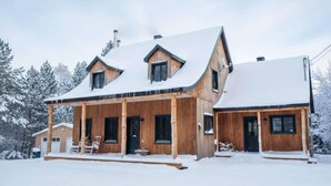 A wooden cabin with a covered porch and a snow-covered roof. - Au Chic Chalet des Chutes | Chic Chalet | Spa (Sainte-Mélanie)