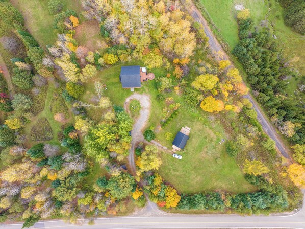 An aerial view of a property with two houses, a driveway, and surrounding trees. - Au Chic Chalet des Chutes | Chic Cottage | Spa (Sainte-Mélanie)