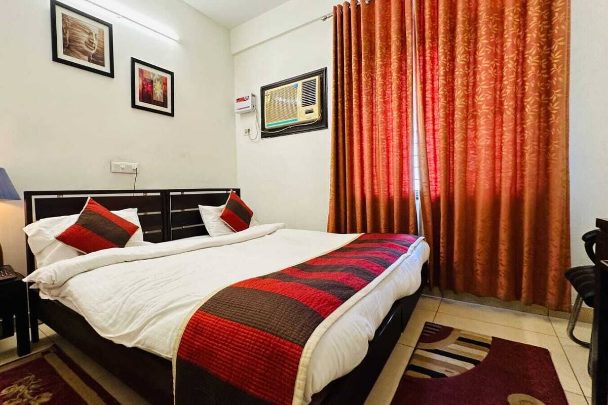 Een hotelkamer met een bed, nachtkastje, lamp en gordijnen.