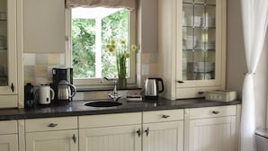 A kitchen with cream-colored cabinets, a black countertop, and a window with a view of greenery.
