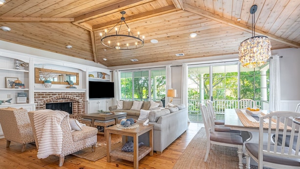A spacious living room with a fireplace, wooden ceiling, and large windows. - Walk to Beach | Updated Tybee Townhome (Tybee Island)