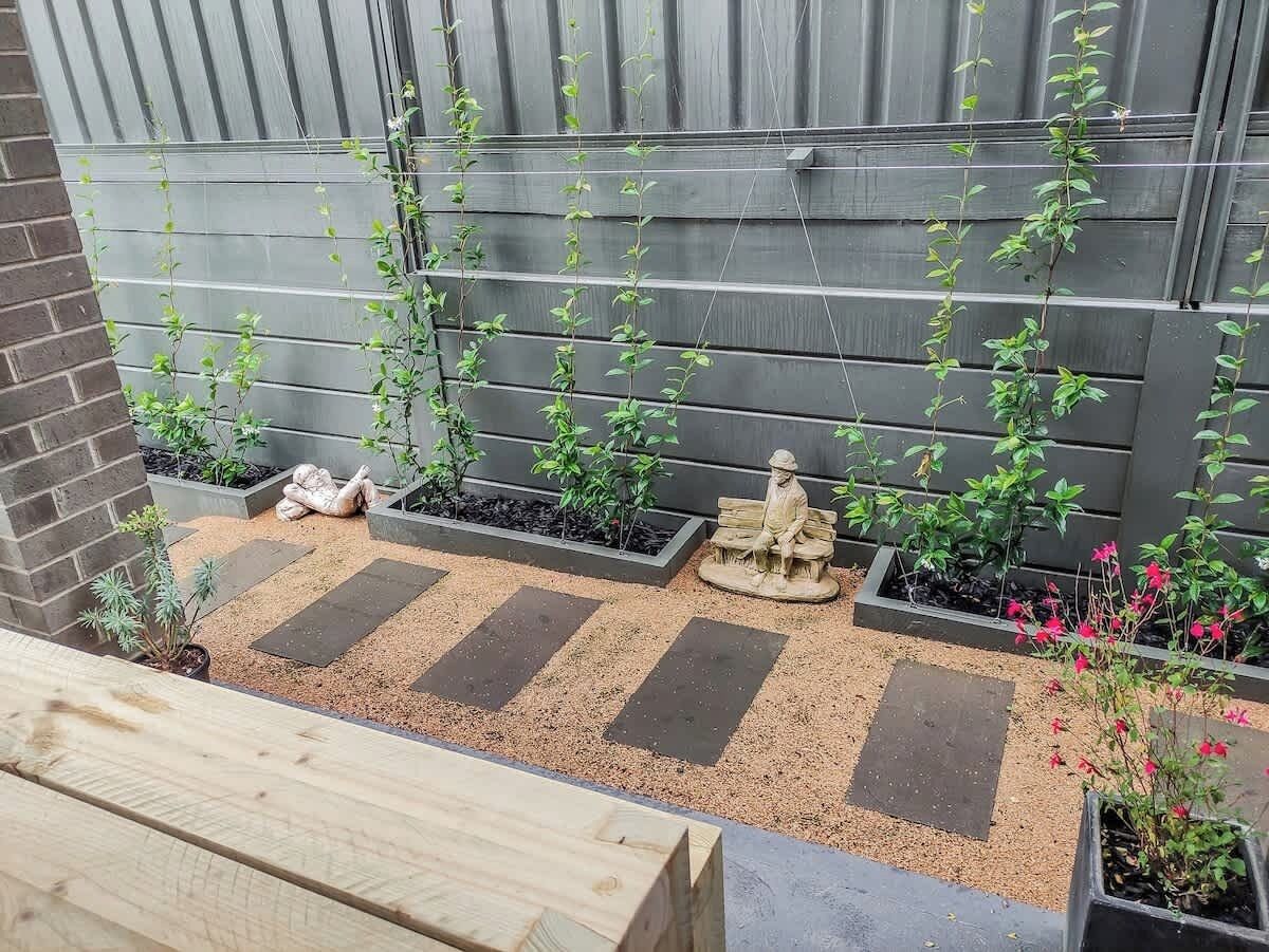 En trädgård med upphöjda rabatter, stenplattor som man kan gå på och en staty.