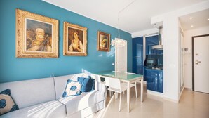 Een moderne woonkamer met een blauwe muur, een witte bank en een glazen eettafel.