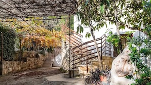 Un escalier en pierre mène à une terrasse en bois dotée d’une rambarde en métal.