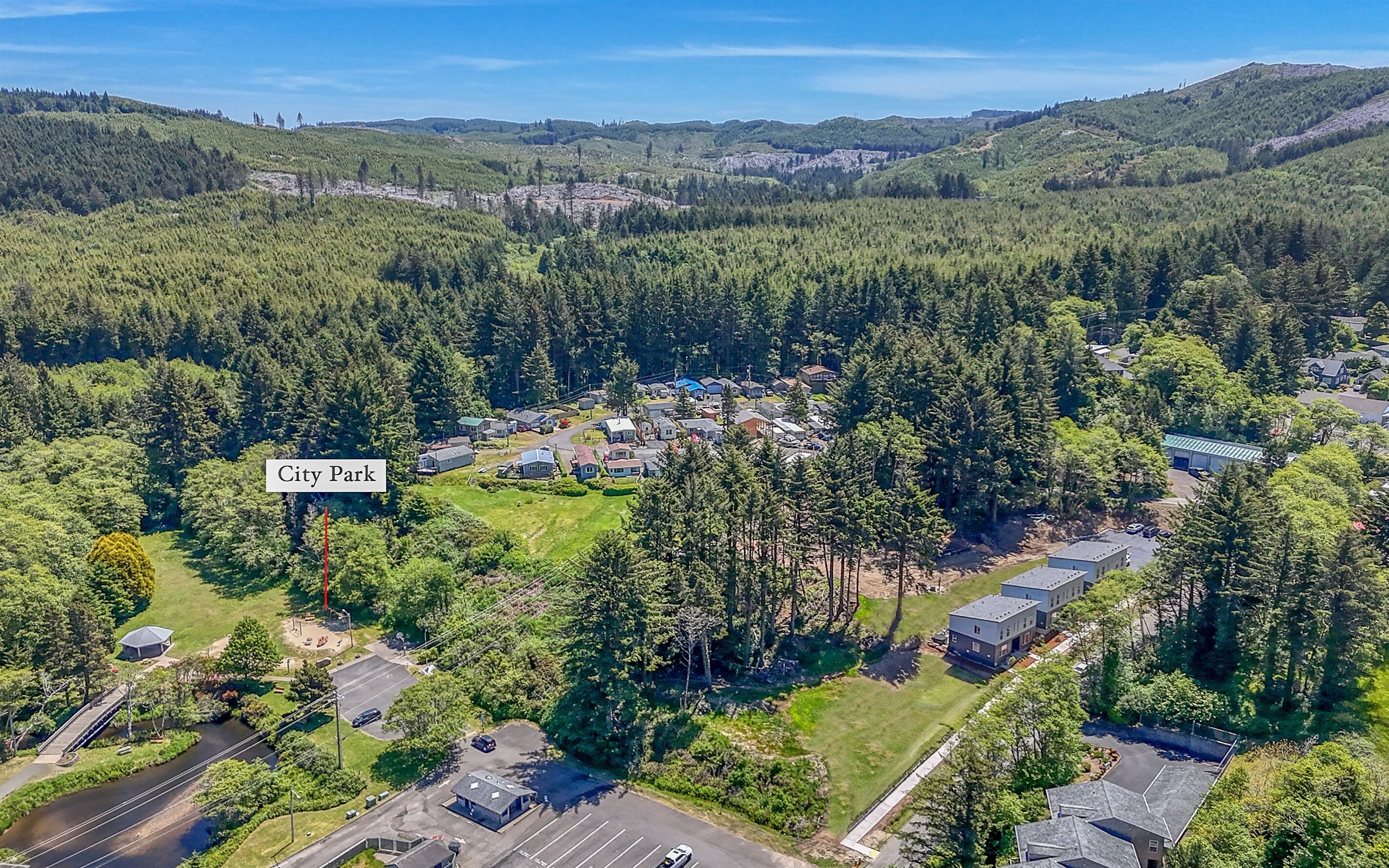An aerial view of a residential area with houses, a park, and a river.