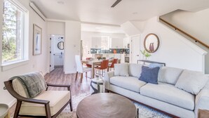 A spacious living area with a sofa, a dining table, and a kitchen in the background.