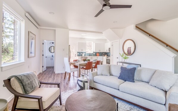 A spacious living area with a sofa, a dining table, and a kitchen in the background.