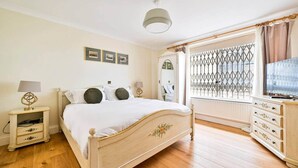 Ein Schlafzimmer mit einem Bett, Nachttischen, einem Schminktisch, einem Spiegel und einem Fenster mit Blick.