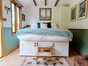 A bedroom with a large bed, a wooden bench, a globe artwork, and a window with a butterfly decoration. - The Botanist - Luxury Cabin With Hot Tub Near York (York)