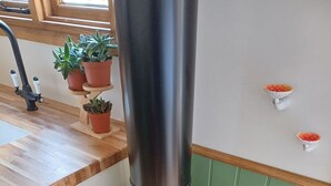 A wood stove with a kettle on top, a sink, and potted plants in the background. - The Botanist - Luxury Cabin With Hot Tub Near York (York)