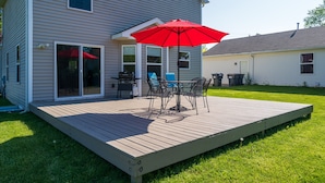 A deck with outdoor furniture and a red umbrella.