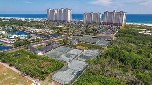 Un complexe hôtelier comprenant plusieurs immeubles de grande hauteur, un port de plaisance et des courts de tennis.