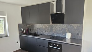 Una cocina moderna con armarios oscuros, salpicadero de mármol y electrodomésticos integrados.