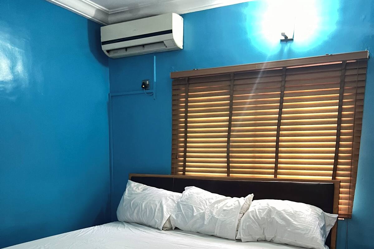A bedroom with a wooden bed, white bedding, and a blue wall.