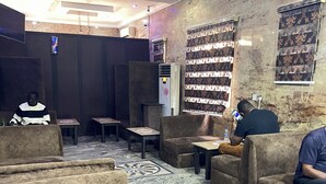 Un hall de hotel con asientos cómodos, piso estampado y una gran pantalla mural.