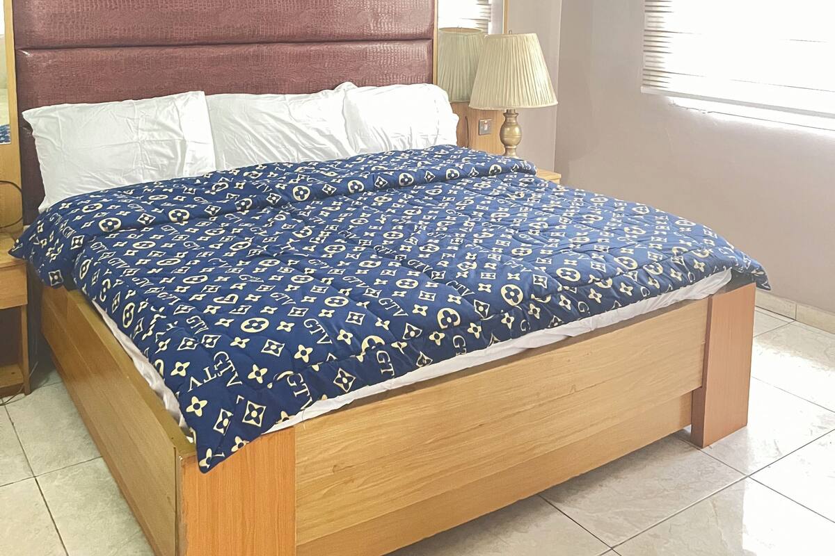 A bedroom with a bed, a nightstand, a mirror, and an air conditioning unit.