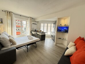 Un appartement moderne comprenant un lit, un canapé, une cuisine et un téléviseur.