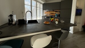 Ett modernt kök med ett stort fönster, en kaffemaskin, en diskho och en frukostplats på köksbänken.