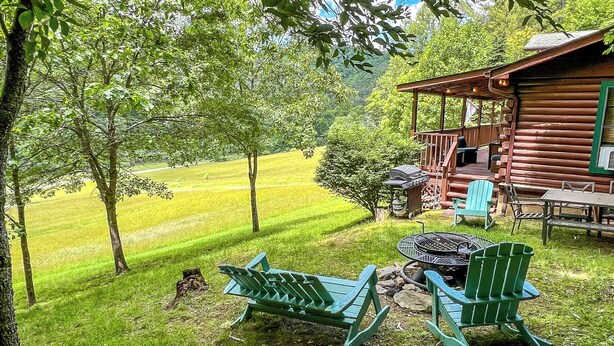 Une cabane en rondins dotée d’une terrasse, d’un espace salon extérieur et d’un foyer.
