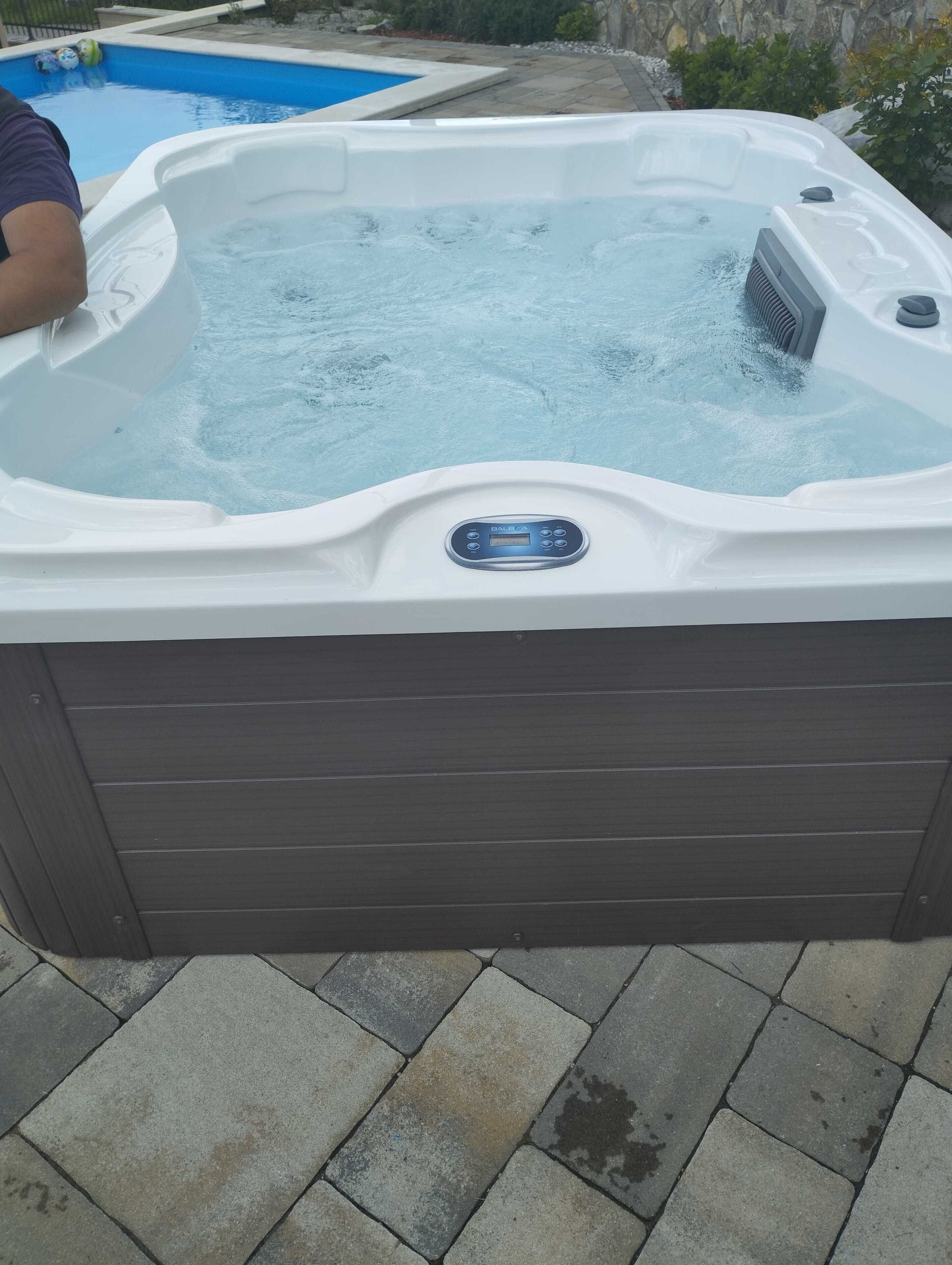 Een jacuzzi met bedieningspaneel, omringd door stenen tegels.
