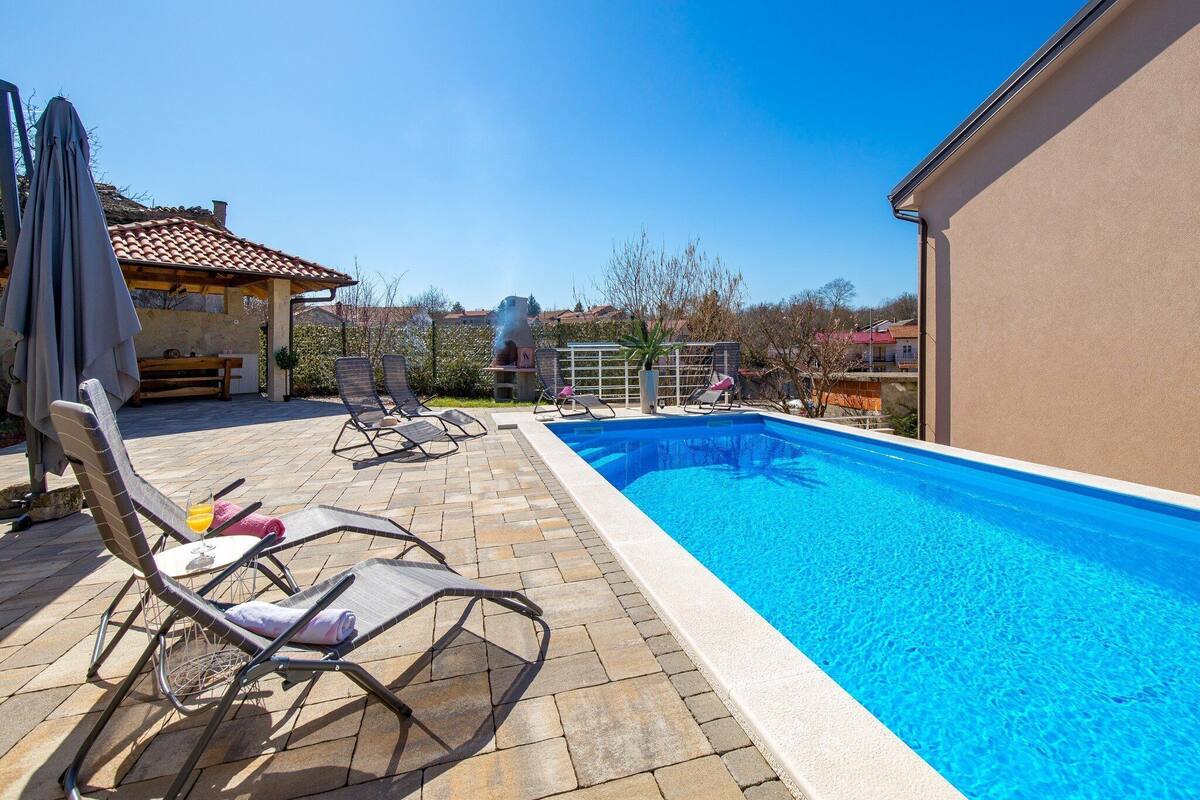 Ein Pool mit Liegestühlen und einer Grillanlage.